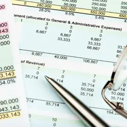 Financial spreadsheet printout with pen and eyeglasses